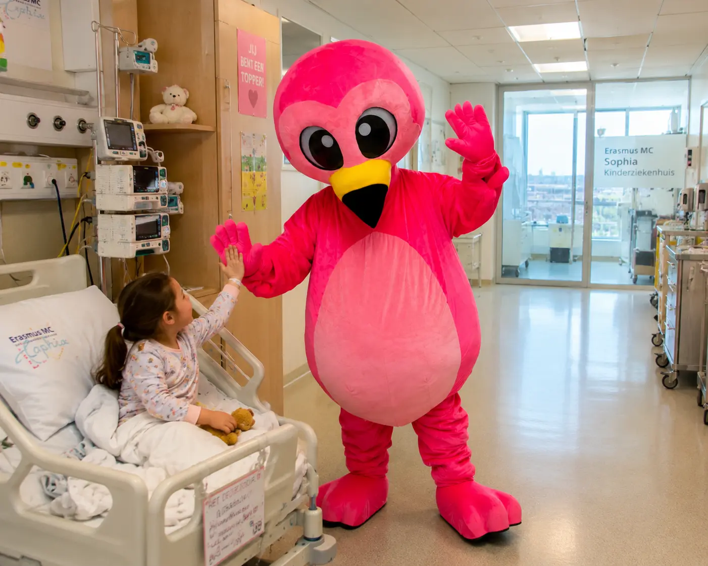 Flami geeft een high-five aan een kind in het Sophia Kinderziekenhuis